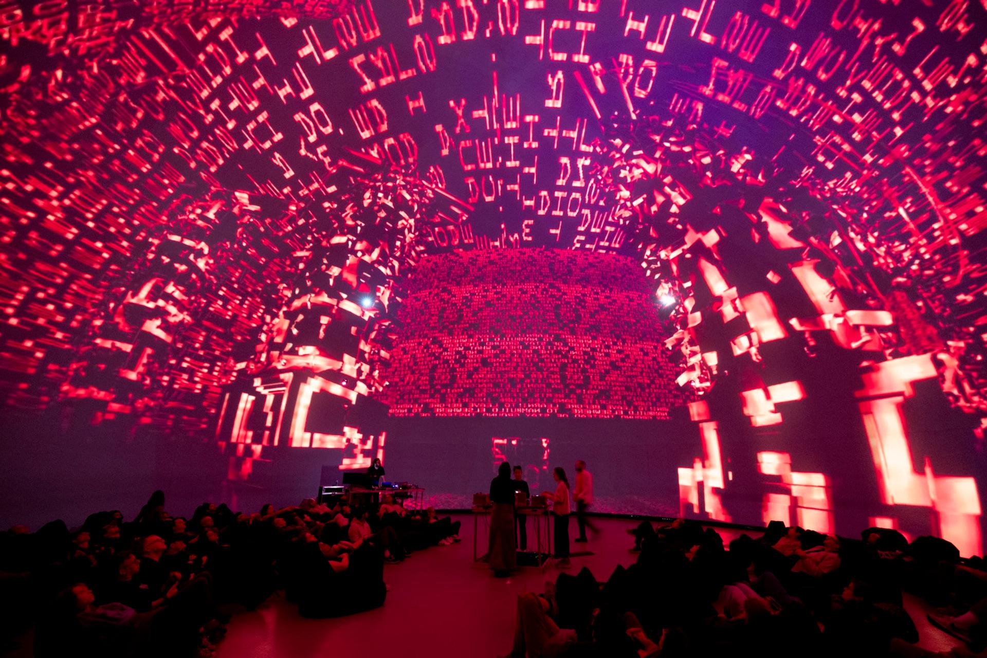 Red glyphs projected across the whole dome above the audience